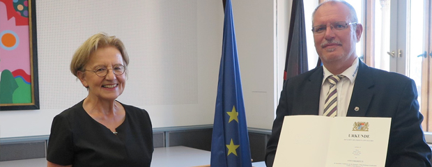 Regierungspräsidentin Maria Els händigt Maiko Alpers DLRG-Steckkreuz aus